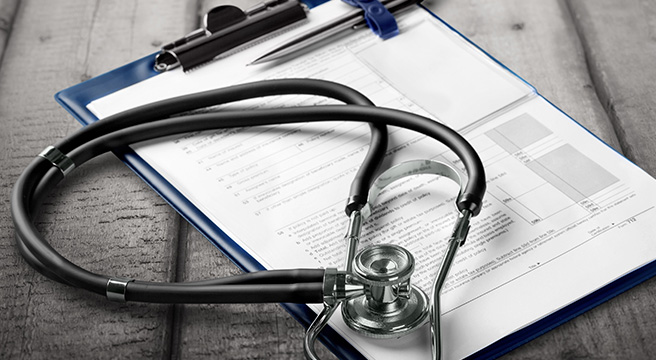Photo: Stethoscope and clipboard with pen and forms to fill